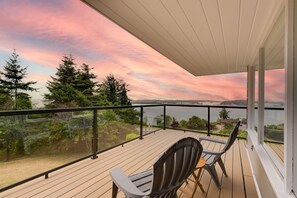 Ein Balkon mit Blick auf einen See und Bäume, eine Holzterrasse und zwei Stühle.