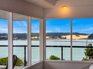 A room with large windows overlooking a lake and hills. - Bay View Dunes Getaway (North Bend)