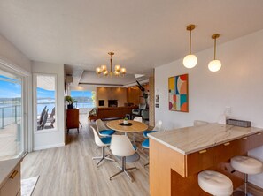 A modern interior with a dining area, kitchen, and a view of the outdoors. - Bay View Dunes Getaway (North Bend)