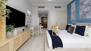 A modern hotel room with a large bed, a desk, and a television. - Elegant Studio Retreat in Damac Hills (Dubai)