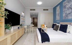 A modern hotel room with a large bed, a desk, and a television. - Elegant Studio Retreat in Damac Hills (Dubai)