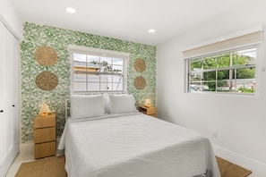 A bedroom with a bed, two bedside tables, a window, and a wall with a leafy pattern. - Tampa Pool Oasis, Lux Boho Design, , Otdr Movie & Kitchen, Near Golf (Tampa)