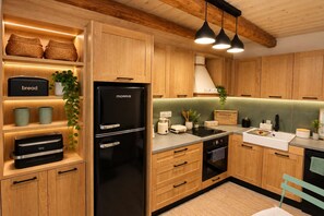 Eine moderne Küche mit Holzschränken, einem schwarzen Kühlschrank und einer Arbeitsplatte mit verschiedenen Geräten.