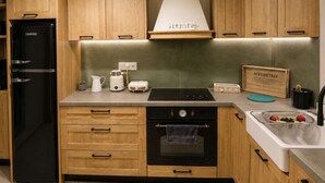 Una cucina moderna con mobili in legno, un frigorifero nero, un fornello e un lavello con un vassoio di servizio.