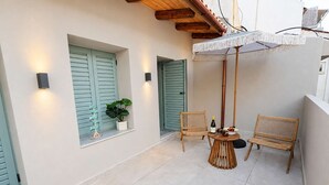 Una piccola zona esterna con due poltrone in vimini, un tavolino rotondo e una pianta in vaso.