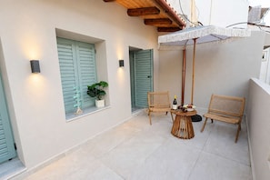 A small outdoor seating area with two wicker chairs, a round table, and a potted plant. - A2 Maisonette - Modern Cretan Living by the Sea (Limenas Chersonisou)
