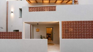 Un interno moderno con un design geometrico a parete, una porta ben visibile che conduce in un'altra stanza e un lampadario.