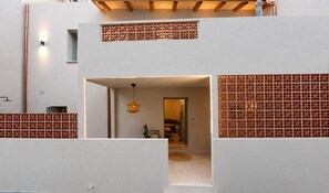 A modern interior with a geometric wall design, a visible door leading to another room, and a hanging light fixture. - A2 Maisonette - Modern Cretan Living by the Sea (Limenas Chersonisou)