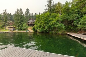 A lakeside property with a dock, a wooden house, and lush greenery. - Bottle Bay Lakefront Lodge | Dock & Game Room (Sagle)
