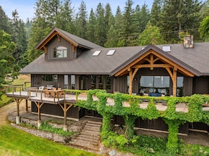 A two-story wooden house with a deck, large windows, and a stone chimney.