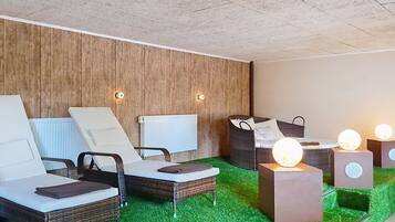 A modern spa area with lounge chairs, a wooden wall, and a green carpet.