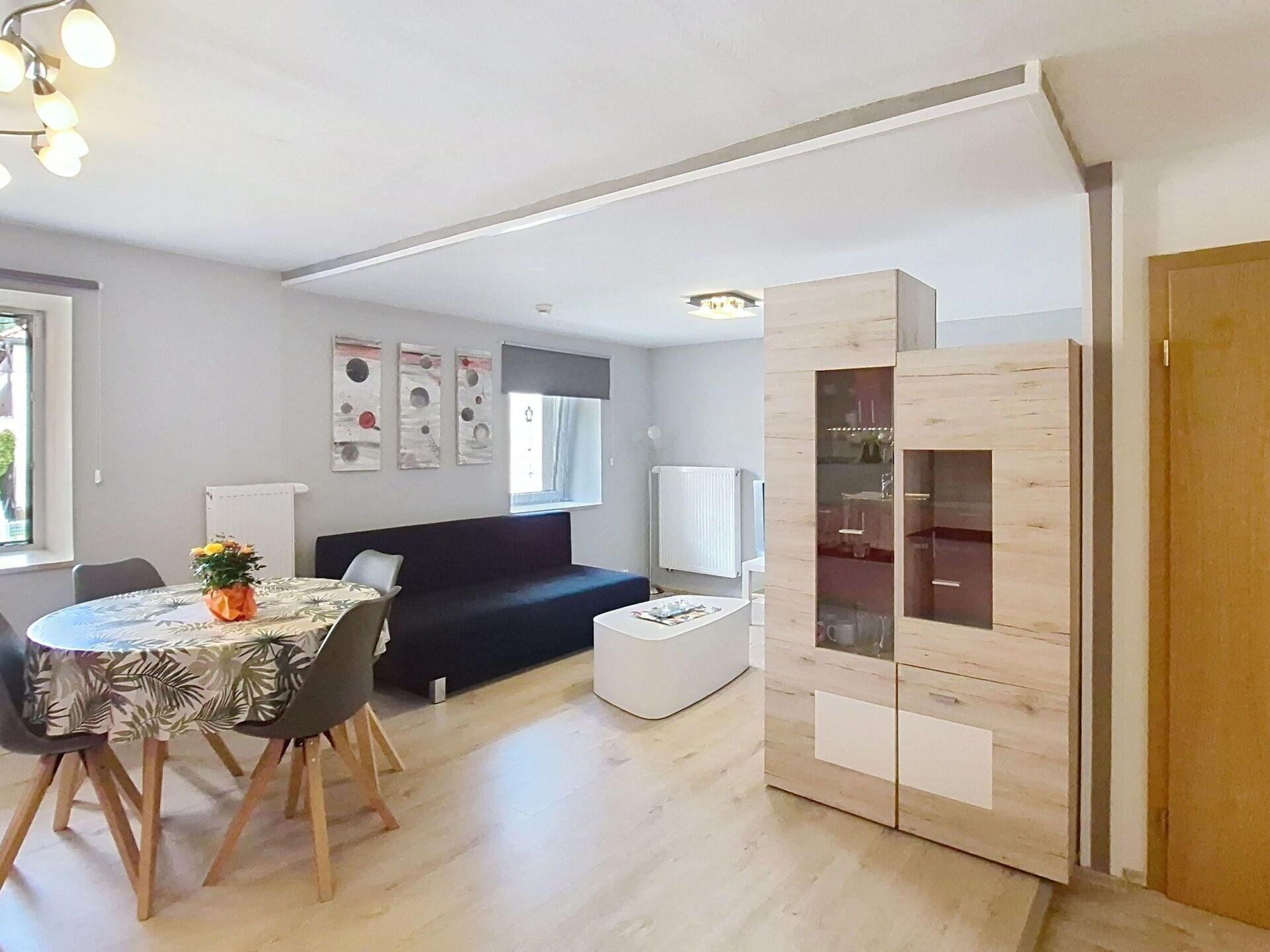 Un espacio habitable moderno con zona de comedor, sofá, mesa de centro y mueble empotrado.