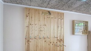 Une armoire en bois dotée de plusieurs crochets, d’une petite étagère et d’un plafond orné d’un motif texturé.