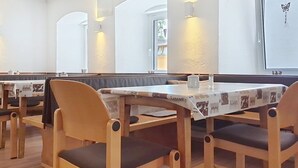 Un restaurant avec des banquettes, des chaises en bois et des tables.