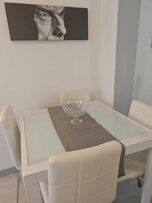 A dining area with a glass table, a central glass bowl, and white chairs. - Apartment with a private pool and garden, just a few minutes from the beach (Pietrasanta)