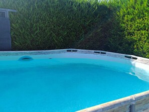 A swimming pool with a stone edge and a small circular opening. - Apartment with a private pool and garden, just a few minutes from the beach (Pietrasanta)