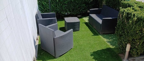 Un patio con mobiliario exterior y césped artificial.