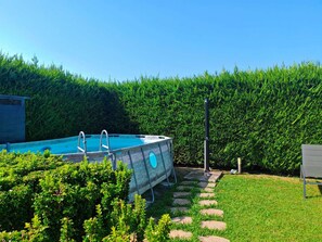 A swimming pool with a wooden deck, surrounded by a hedge and a stone pathway. - Apartment with a private pool and garden, just a few minutes from the beach (Pietrasanta)