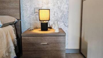 Ein Nachttisch aus Holz mit einer Lampe, einer Schublade und einem an der Wand befestigten Lichtschalter.