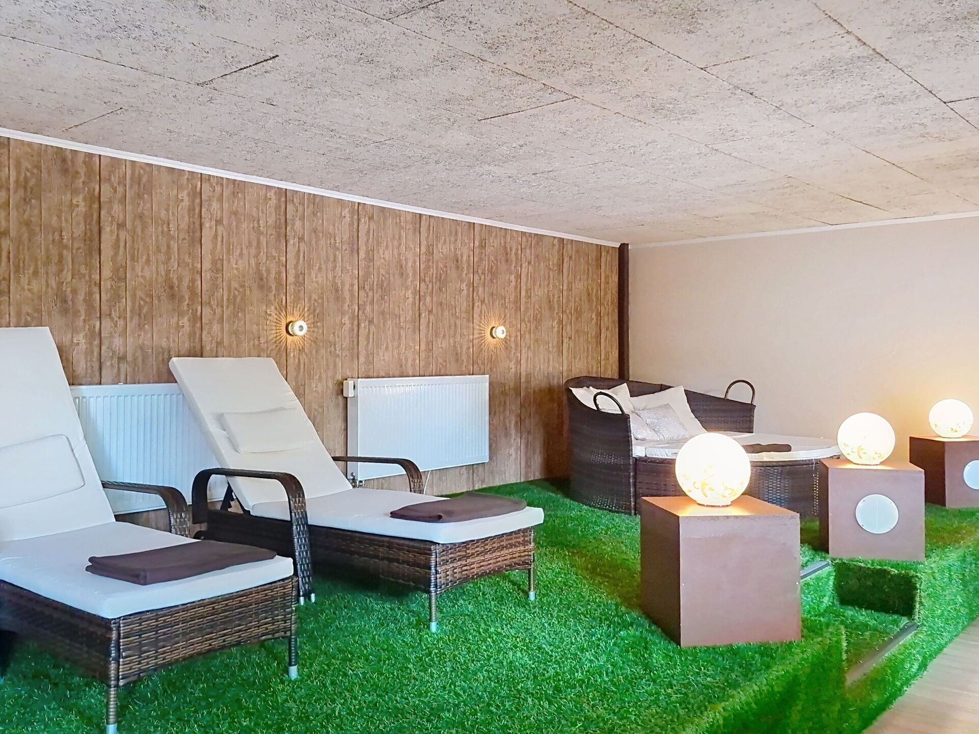 A modern spa area with lounge chairs, a wooden wall, and a green carpet.