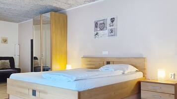 A bedroom with a wooden bed, bedside tables, a mirror, and wall art.