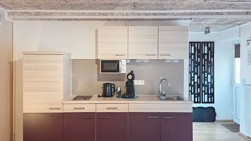 A modern kitchen with a microwave, coffee maker, and sink.