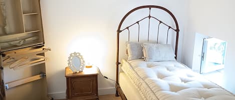 Une chambre à coucher comprenant un lit, une table de chevet, une commode et une étagère fixée au mur.