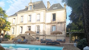 Um edifício grande com piscina, área de estar ao ar livre e um pergolado.
