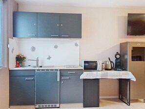 A compact kitchen with grey cabinets, a microwave, a kettle, and a small refrigerator. - Nice apartment for 2 people with WIFI, TV, terrace and pets allowed (Freundorf)