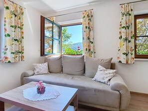 A room with a sofa, a table with a glass jar, and a window with curtains.