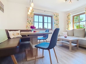A modern living room with a dining area, a sofa, a coffee table, and a window with curtains.