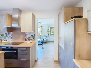 A modern kitchen with a dishwasher, a refrigerator, and a dining area with a sofa and a table.
