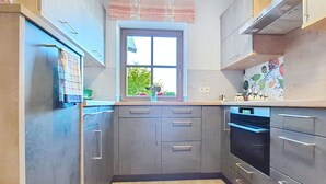 A compact kitchen with grey cabinets, a window, and a built-in oven.