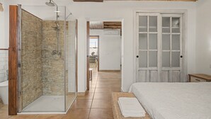 Un dormitorio con cama, cabina de ducha de vidrio y puerta de madera.