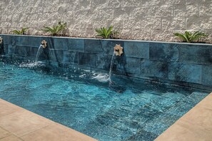 A swimming pool with water jets, surrounded by a stone wall and small plants. - Tartesos 6 with private pool, Wi-Fi and air conditioning (Conil de la Frontera)