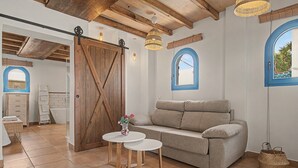 Una habitación acogedora con puerta de madera, un sofá, una mesita y una ventana con vistas.