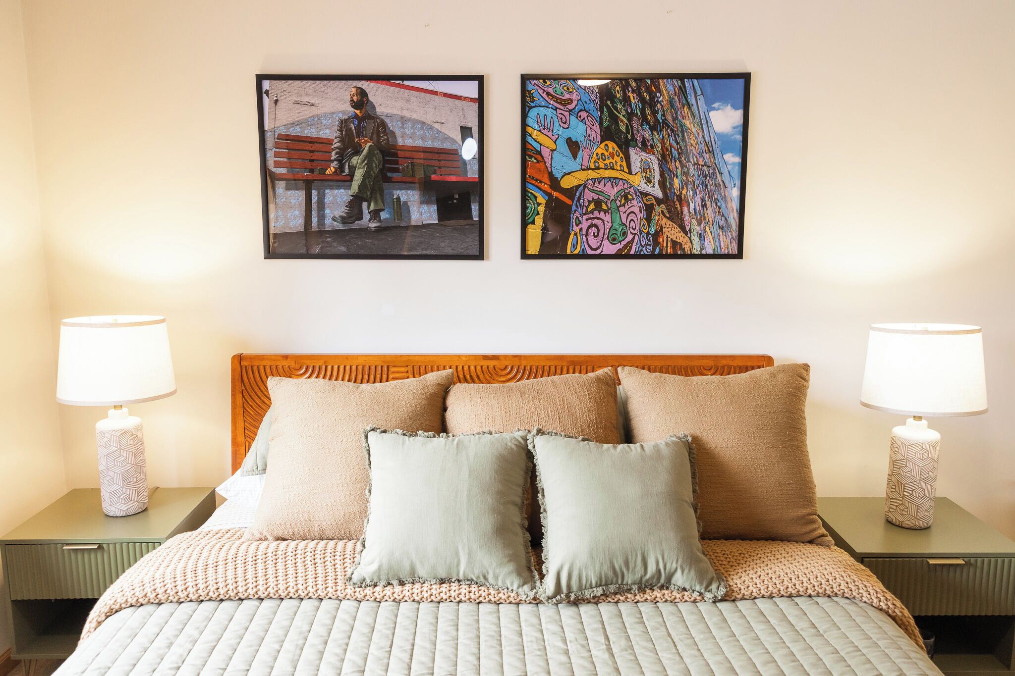 Ein Hotelzimmer mit einem Bett, zwei Nachttischen, zwei Lampen und zwei gerahmten Kunstwerken an der Wand.