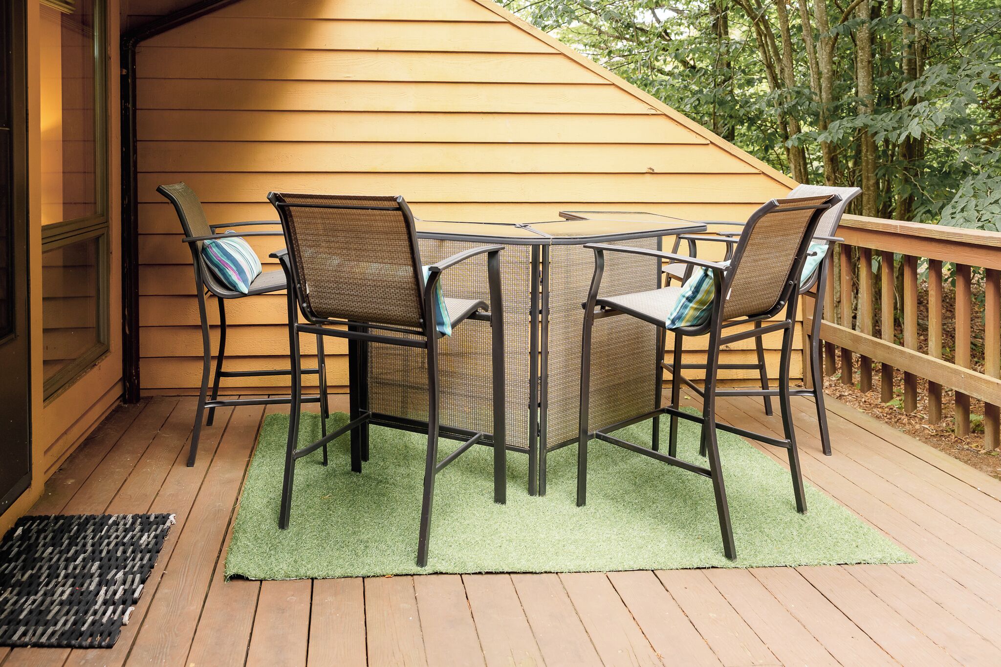 Eine Terrassenanlage im Freien mit Tisch und Stühlen, einer Holzterrasse und einer grünen Matte.