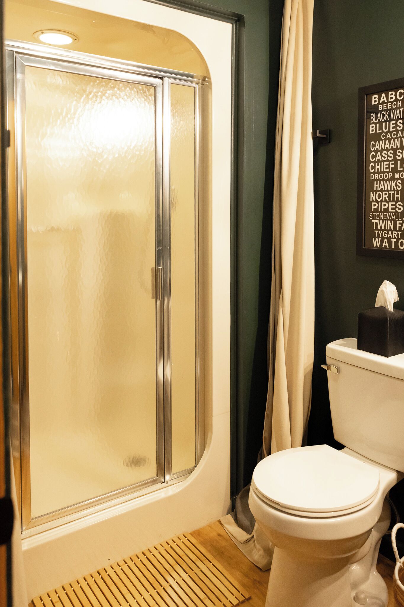 Une salle de bain équipée d’une douche, de toilettes et d’un panneau mural avec du texte.