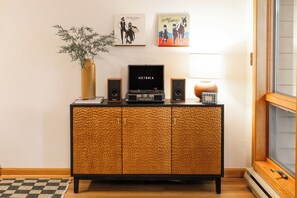 A wooden cabinet with a record player, speakers, and a vase with green foliage.