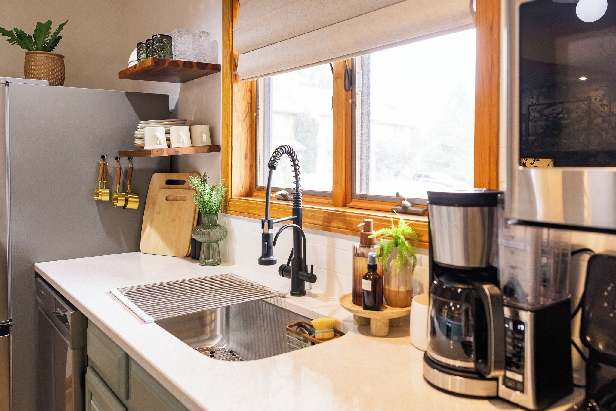 A kitchen with a stainless steel sink, a coffee maker, and a window with a view.