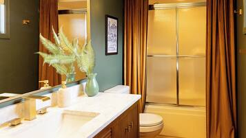A bathroom with a white sink, a toilet, and a shower with frosted glass doors.