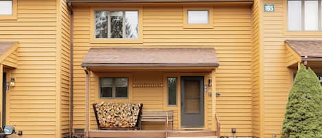 Un bâtiment jaune à deux étages, doté d’un porche à l’avant, d’une porte et d’une petite fenêtre.