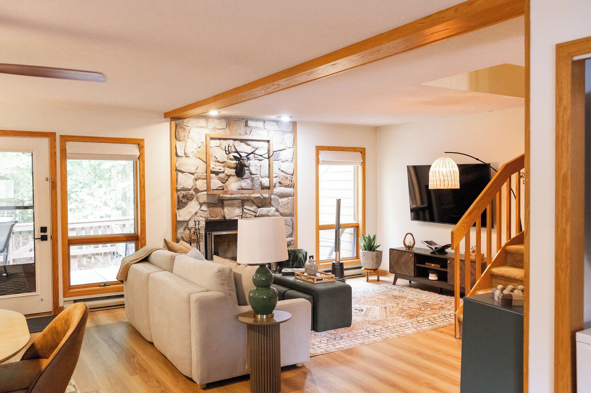 A modern living room with a stone fireplace, a sofa, a coffee table, and a television.