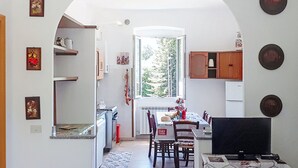 Uma cozinha compacta com área de refeições, TV e janela com vista para árvores.