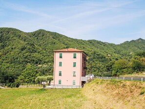 Ein pinkfarbenes Gebäude mit vielen Fenstern, das an einem Hügel mit Blick auf Berge steht.