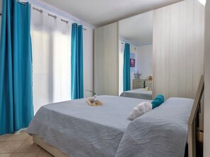 Ein Schlafzimmer mit zwei Betten, einem großen Spiegel und blauen Vorhängen.
