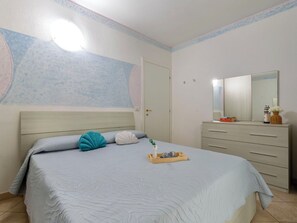 Une chambre à coucher comprenant un lit, une commode, un miroir et un mur avec un luminaire.