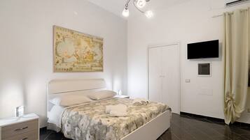 A bedroom with a bed, a nightstand, a television, and a wall-mounted air conditioner.