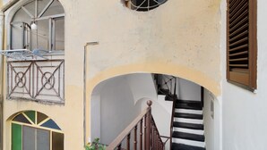 Un edificio con una scala, una finestra con una griglia metallica e una porta con un motivo geometrico.